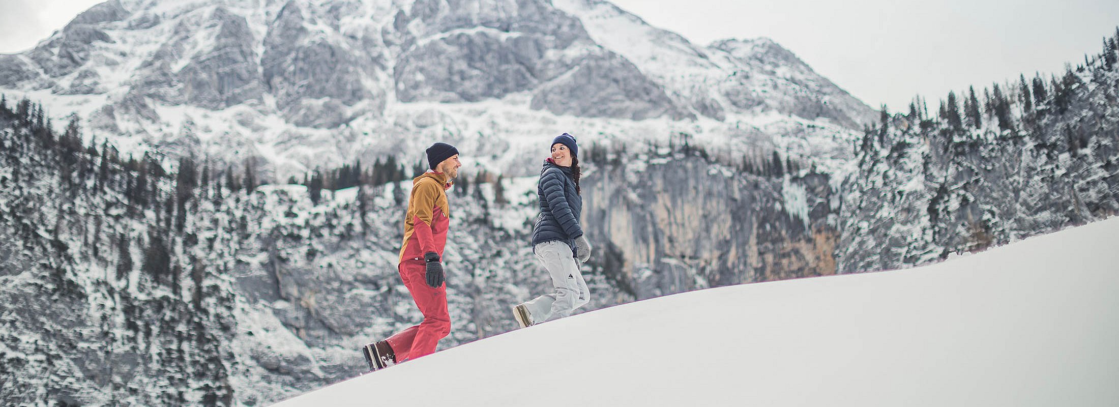 Zwei Personen beim Schneeschuhwandern im Tiefschnee vor beeindruckender Bergkulisse