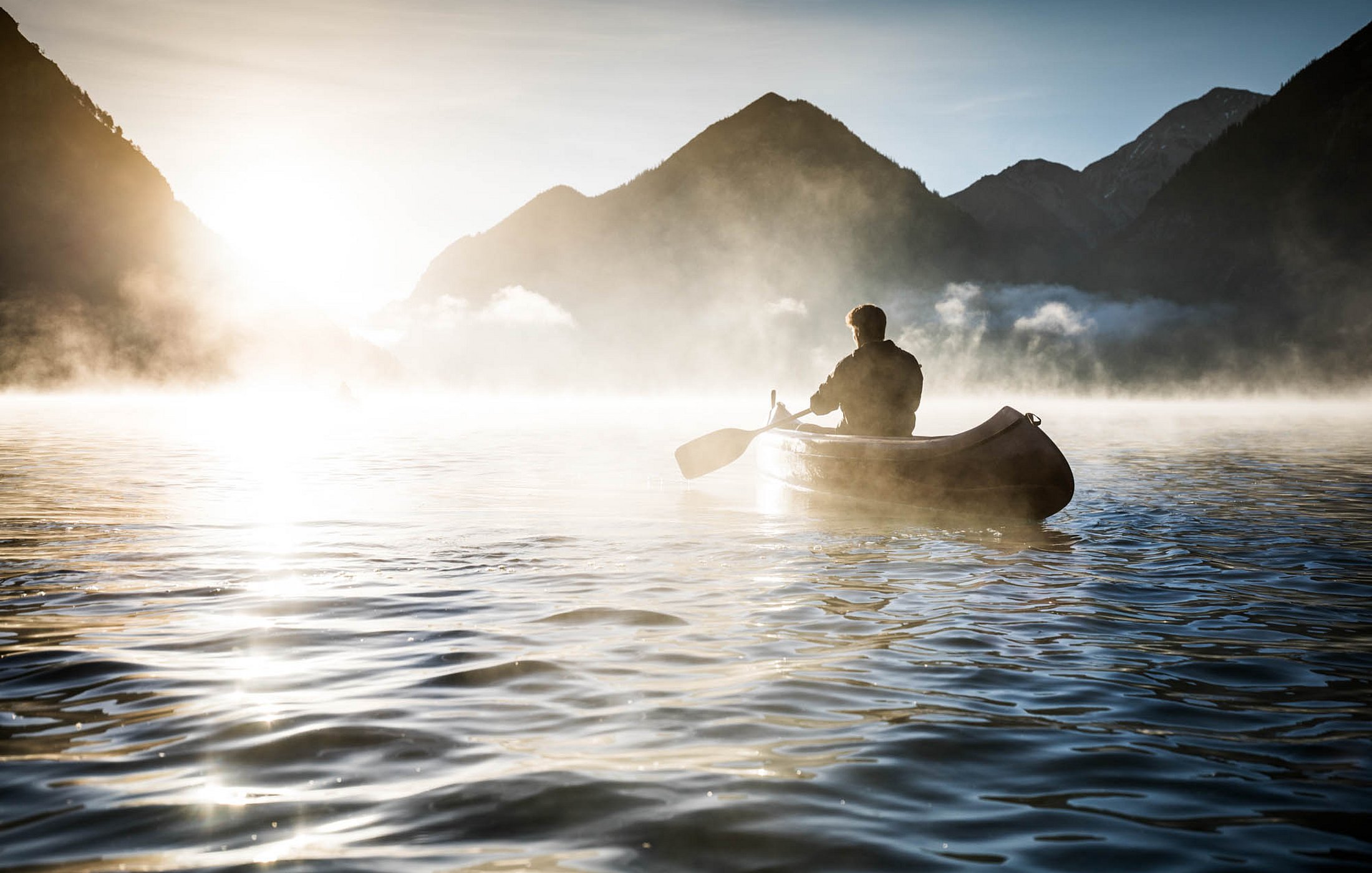 Kanufahrer im Morgennebel auf dem Heiterwanger See in den Bergen